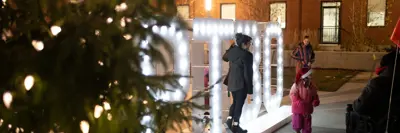 Illuminated PTBO sign in Quaker Foods City Square next to holiday tree at night